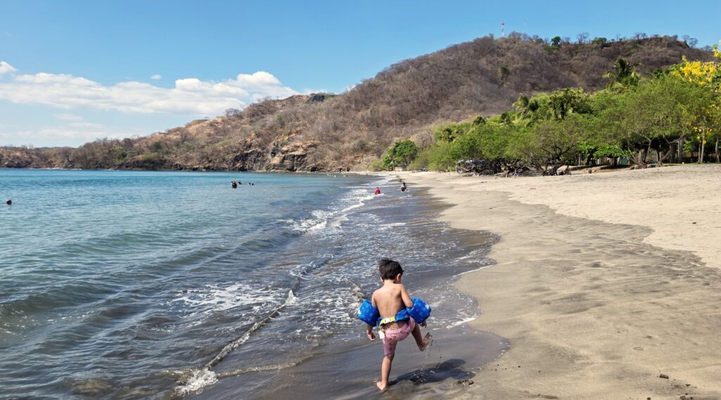 Kid playing on beaches near Liberia Airport with dry vegetation